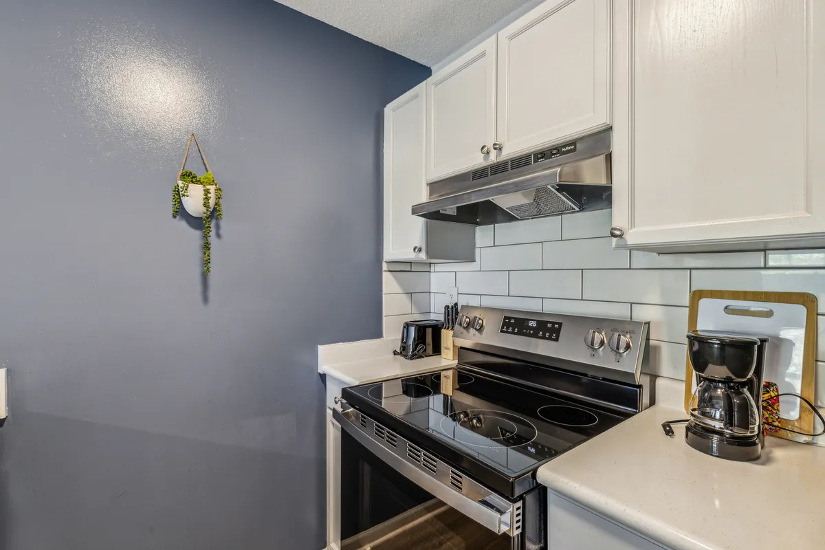 A kitchen with gleaming stainless steel appliances, crisp white cabinetry, and a blue accent wall. The environment is inviting and functional, highlighting the ease of making coffee, sharing recipes, or cooking together.