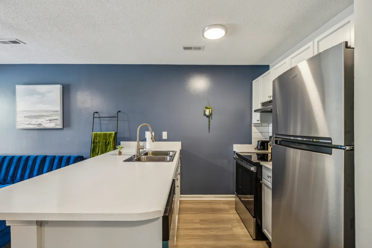 A well-lit kitchen featuring a large island, sleek stainless steel appliances, and a vibrant blue accent wall. The open layout encourages social interaction and showcases the kitchen as a central hub for dining and meal prep.