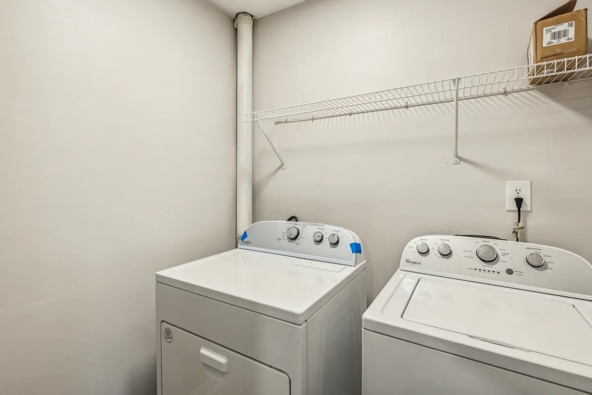 A neatly organized laundry area with a washing machine, dryer, and a shelf stocked with laundry supplies. The functional layout emphasizes ease of use and everyday practicality, making the space feel efficient and welcoming.